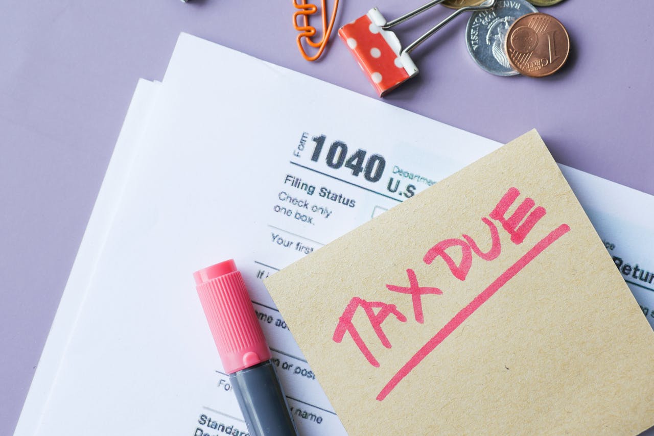 Close-up of IRS Form 1040 with Tax Due note and stationery on a desk.